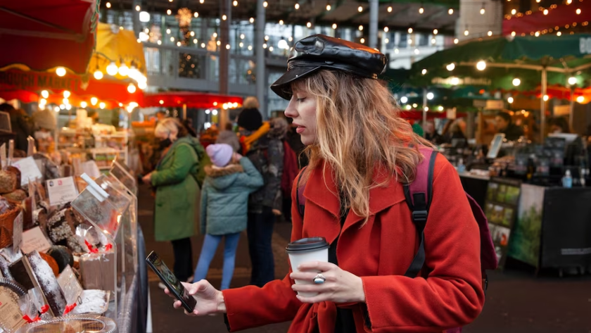 Girl in red coat and hat capturing a cake outdoor Christmas bazaar.