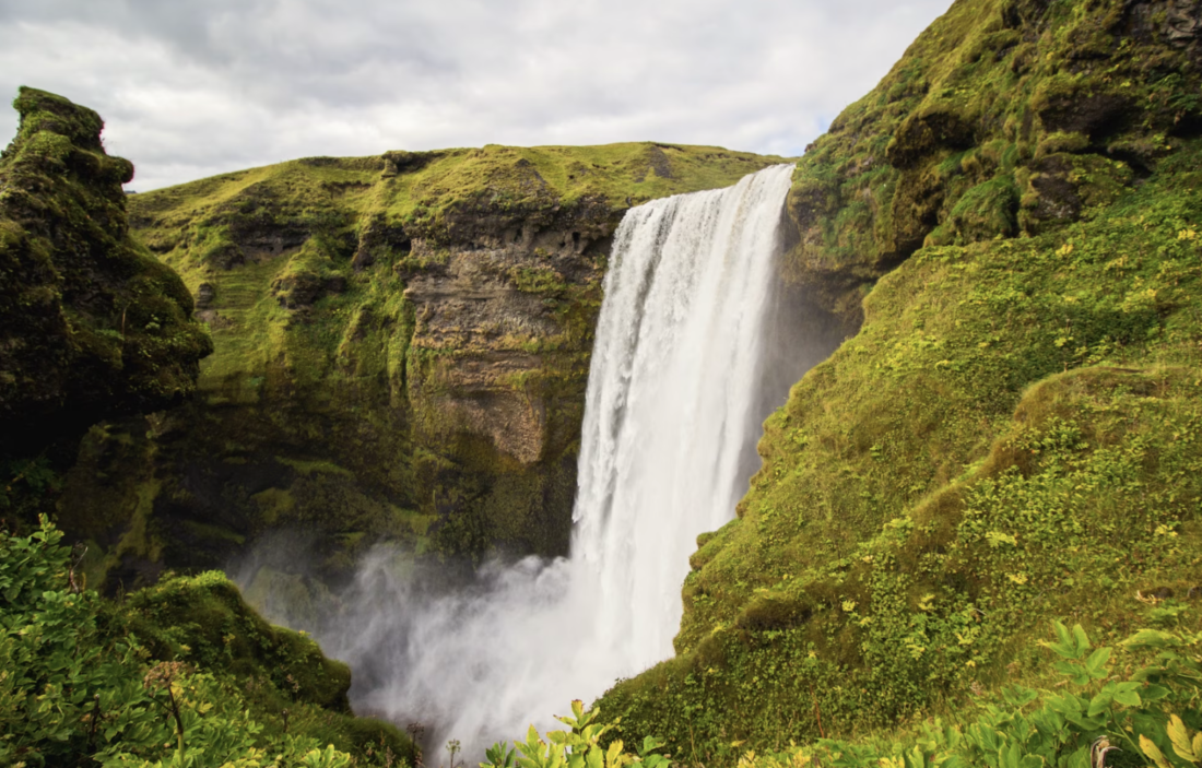 A waterfall surrounded by green mountains.