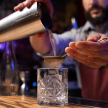 Bartender crafting drinks on a bar counter.